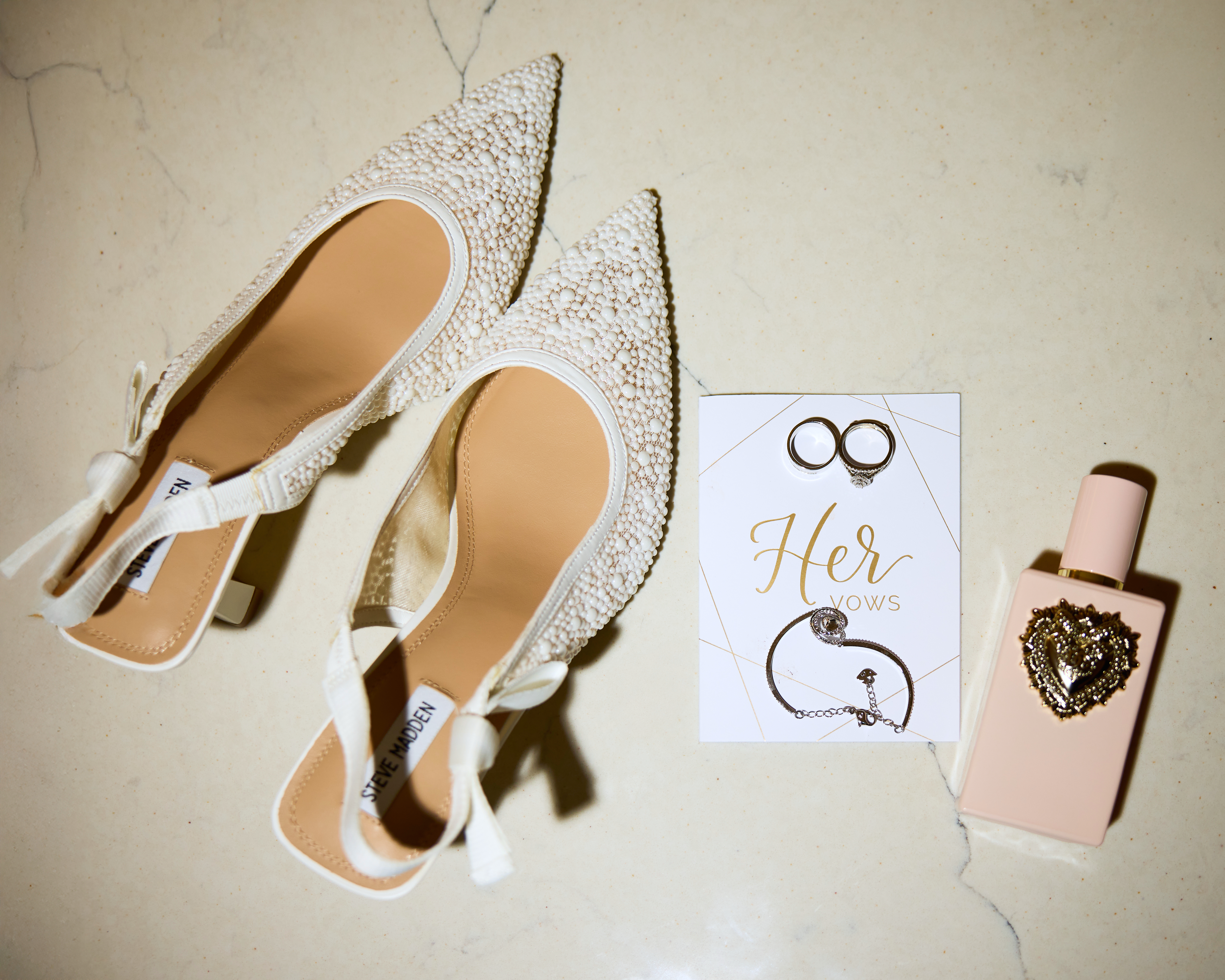 Bridal details - pearl heels, rings, vow card and perfume