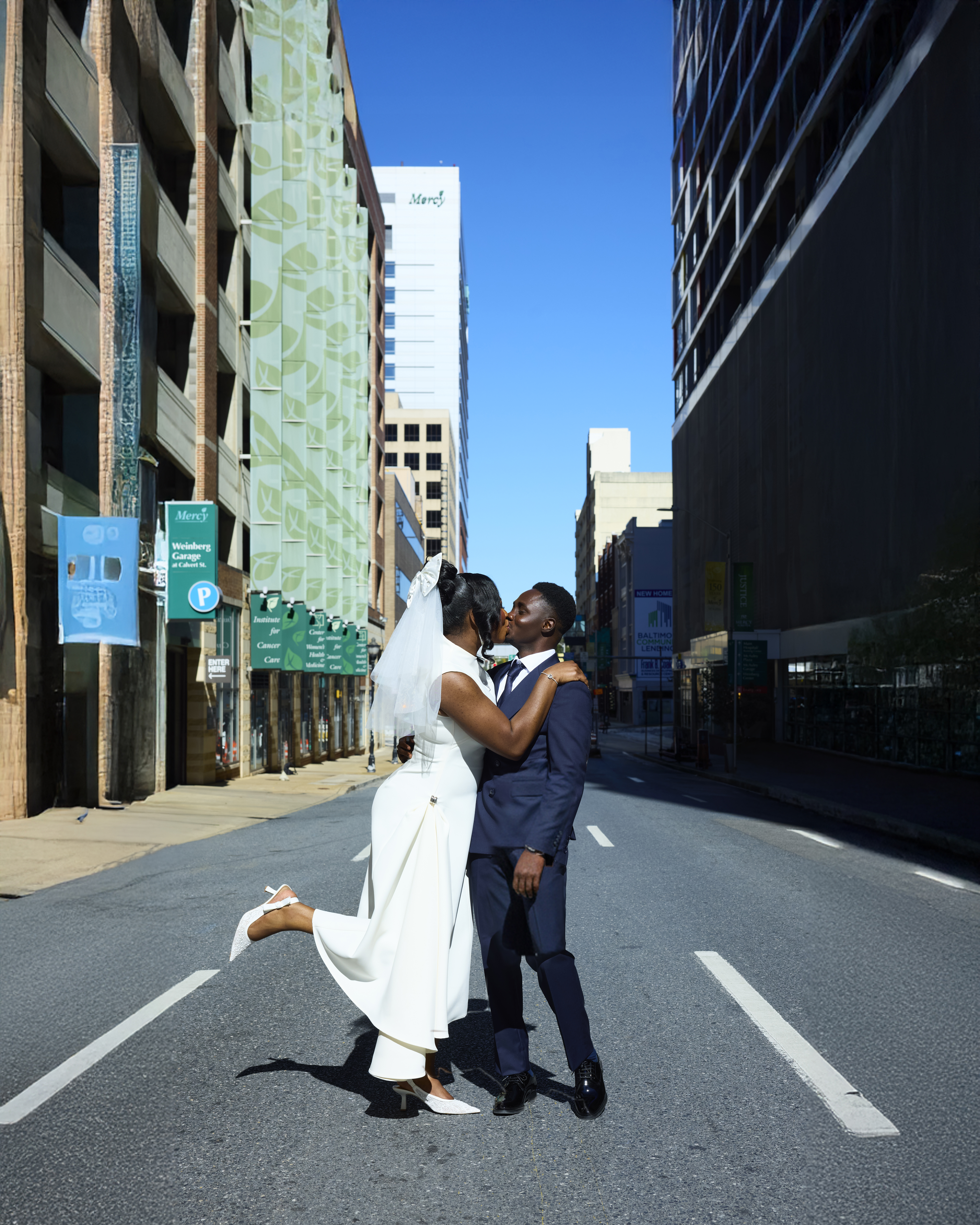Bride kicking up her heel while kissing the groom on a city street