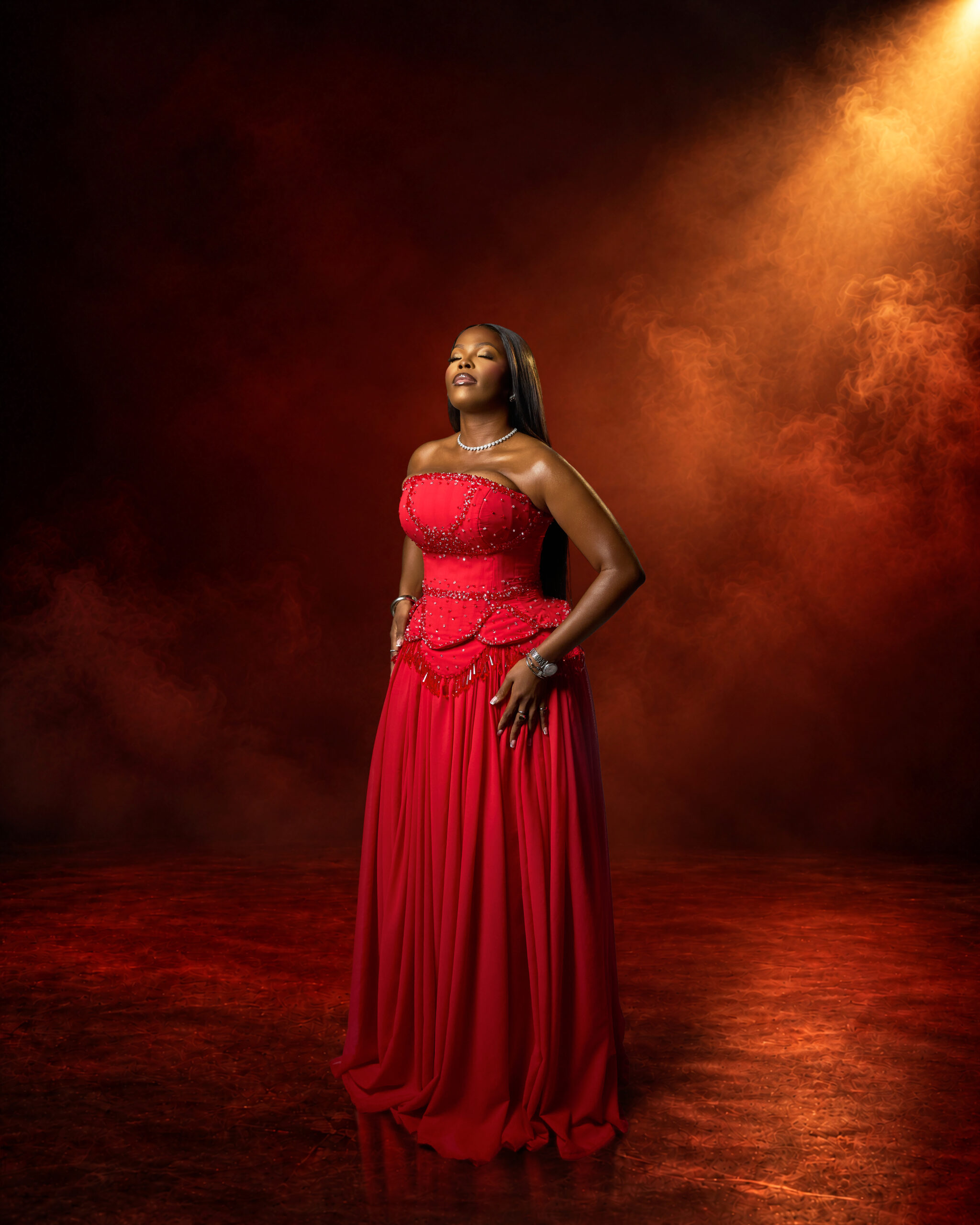 Woman in a red gown under a warm spotlight