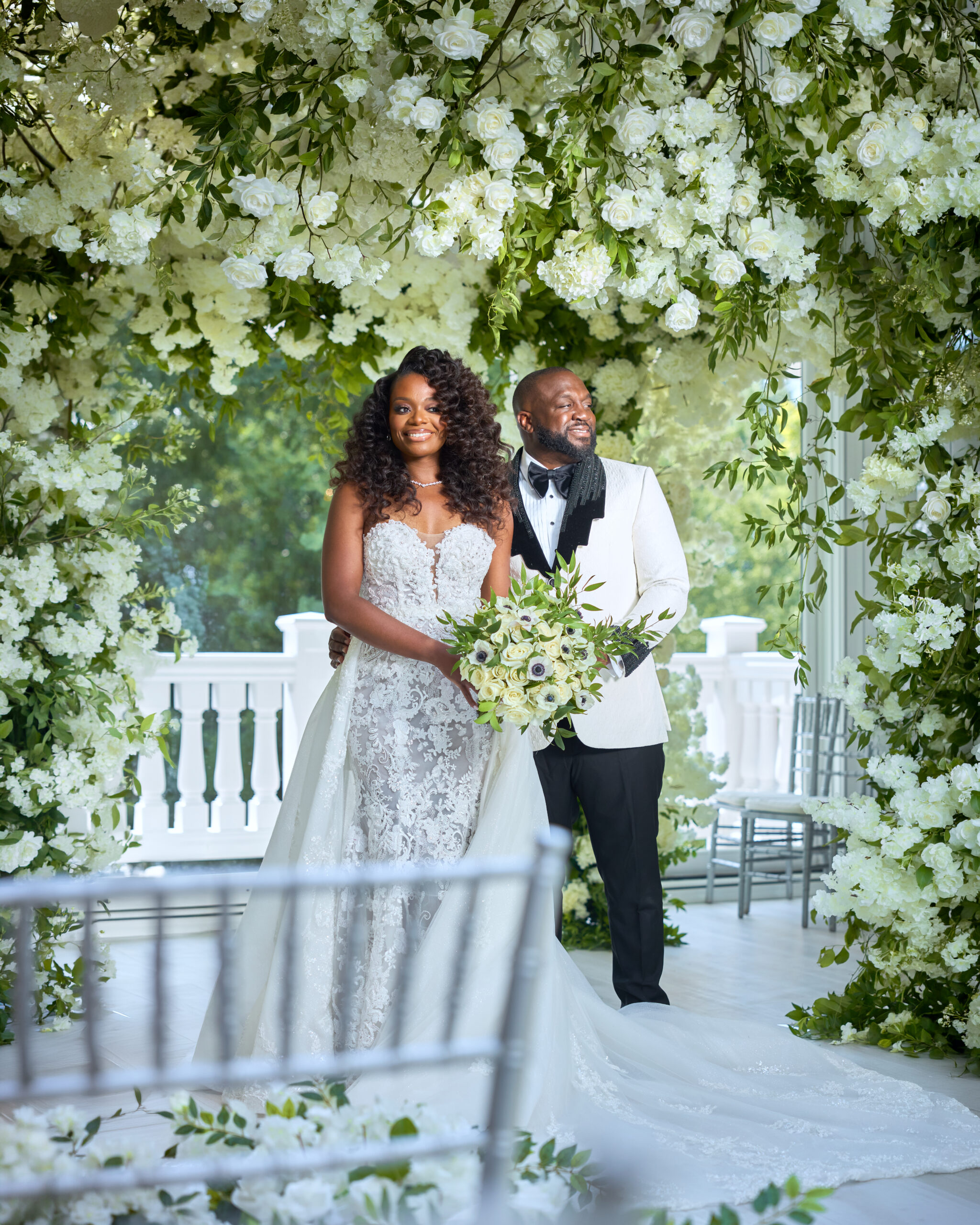 Bride and groom beneath a white floral arch