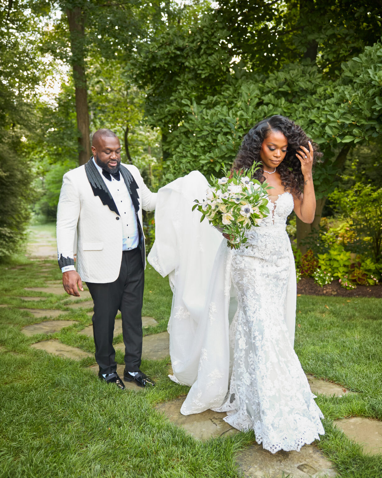 Groom gently lifting the bride's train in a garden